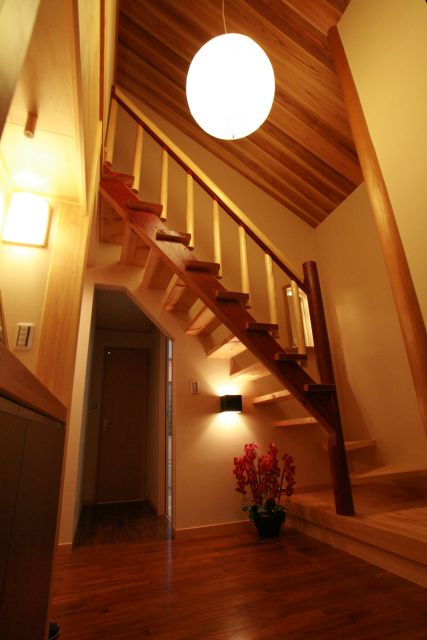 階段下からの明かりが柔らかい空間を演出する北山杉の手摺が映える居間と一体の吹抜け階段。