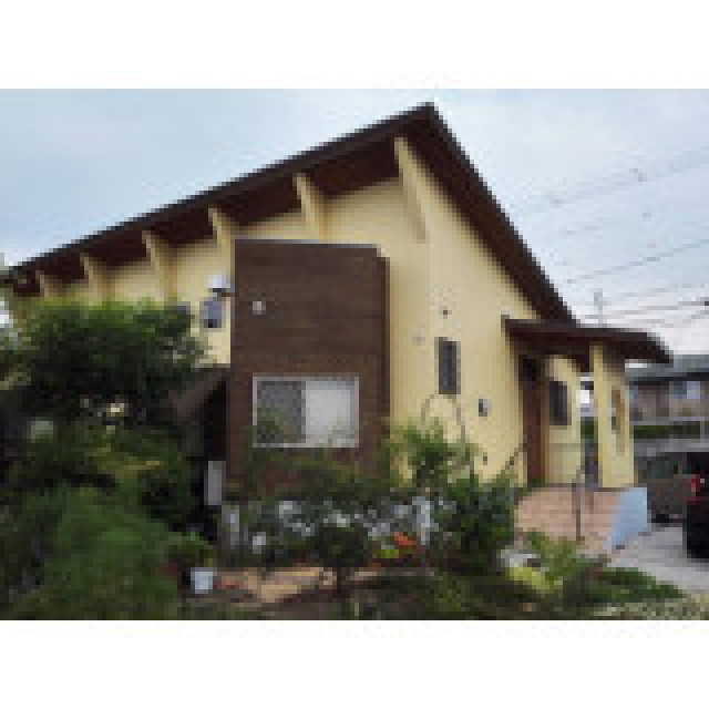 池のほとりにある木造平屋建て住宅の外観を、アクセントとなるダークブラウン木目板張りとして、植栽のグリーンによく合うクリームイエローの外壁塗装を施しました。