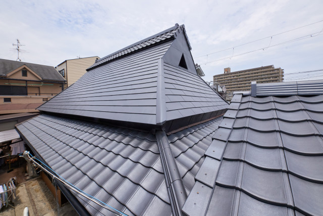茅葺き屋根を温存したまま、上部の屋根の張り替えをご提案。最新の機能性をもちながらも、和風屋根を表現できるルーガ（軽量瓦）とガルバリウム鋼板を使った一文字葺きの組み合わせでご提案いたしました。
